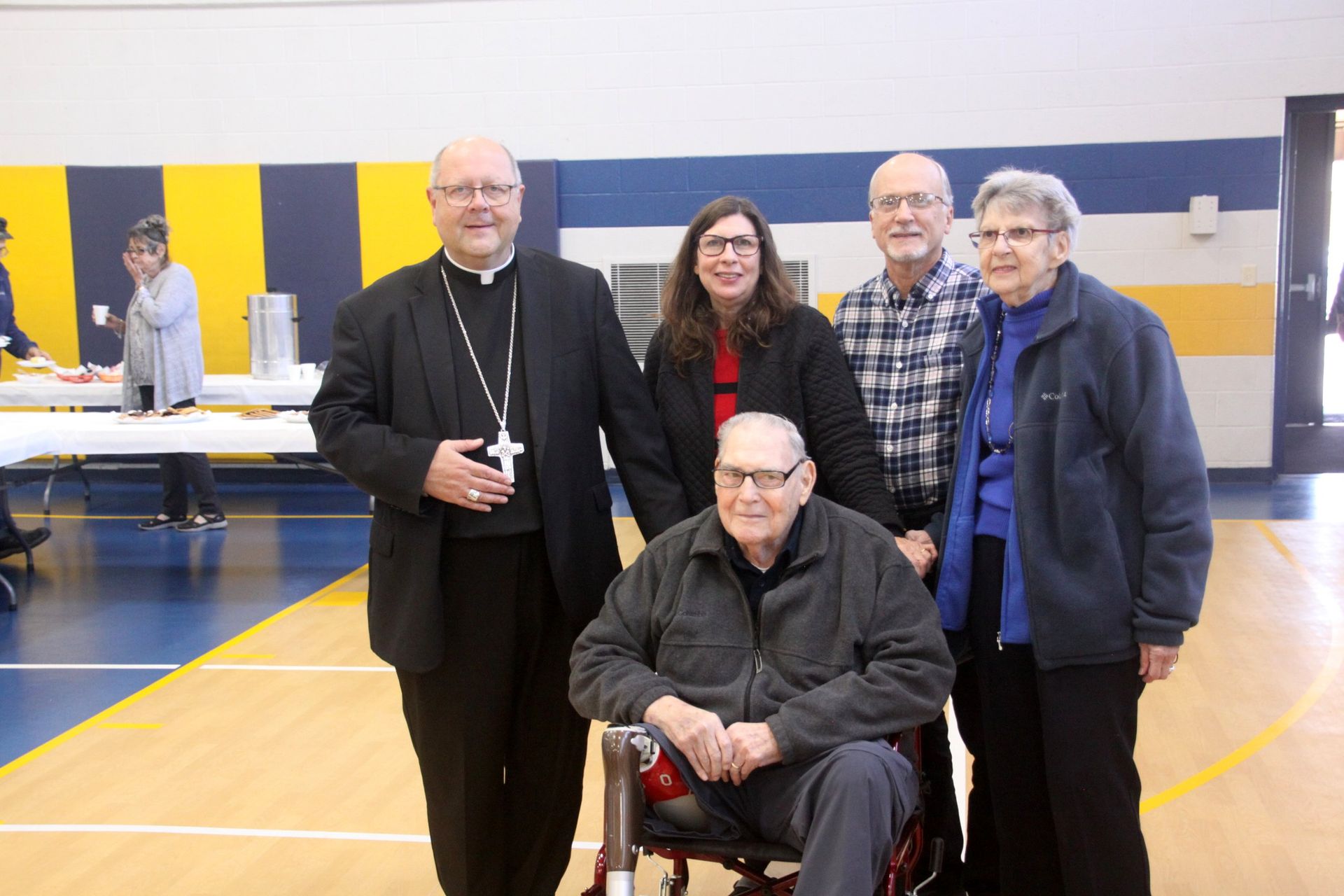 A group of people standing around a man in a wheelchair.