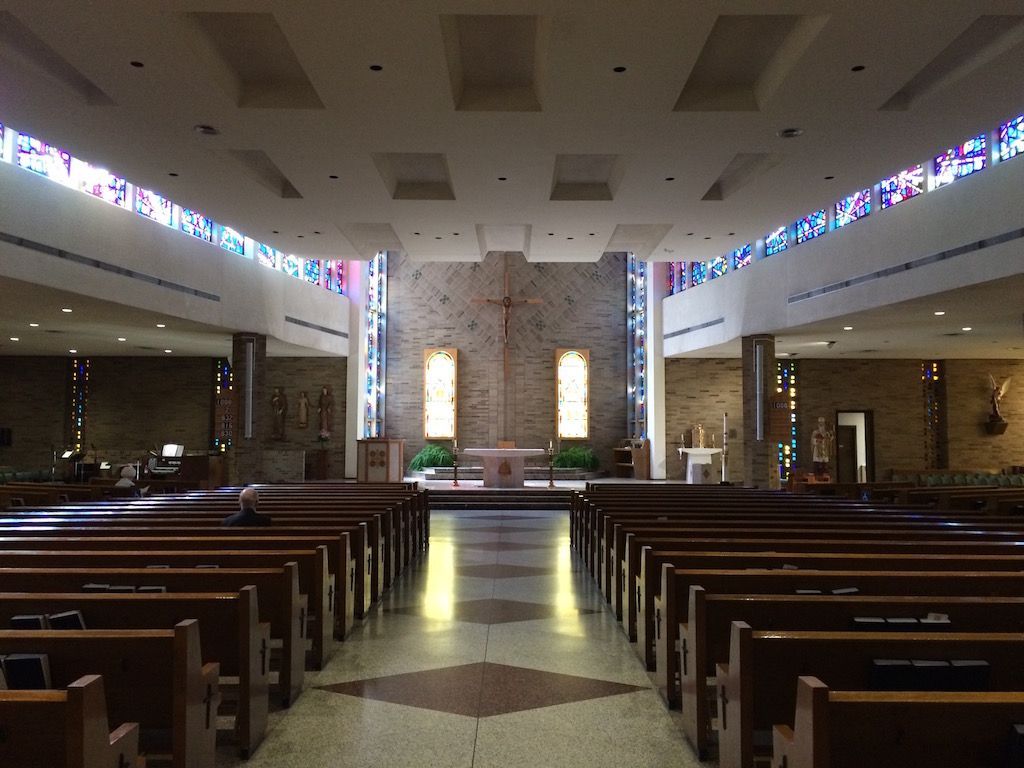 A church with rows of wooden benches and stained glass windows