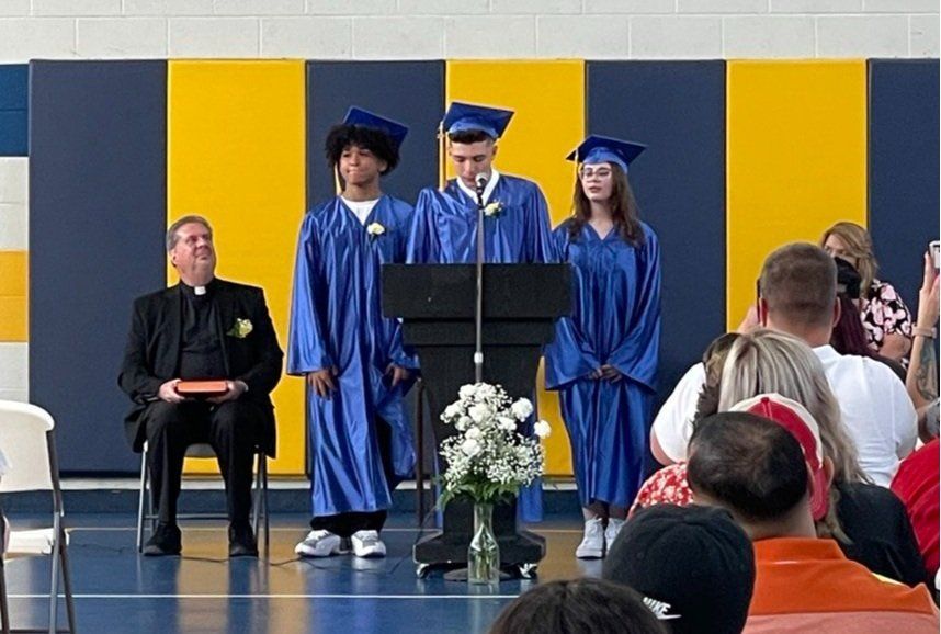 A group of graduates are standing at a podium giving a speech.