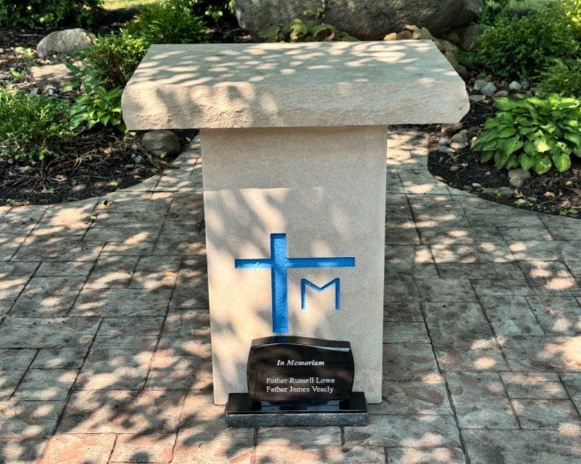 A stone pedestal with a blue cross and the letter m on it