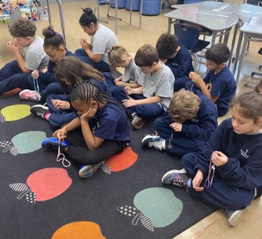 A group of children are sitting on a rug with apples on it