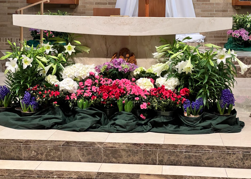 A church altar decorated with flowers and plants.