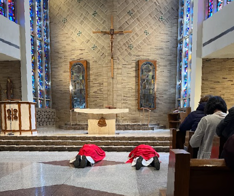 Two clergy are kneeling in front of the altar