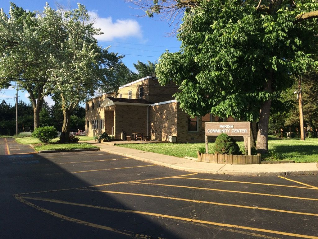 A parking lot with a building in the background and trees in the foreground.