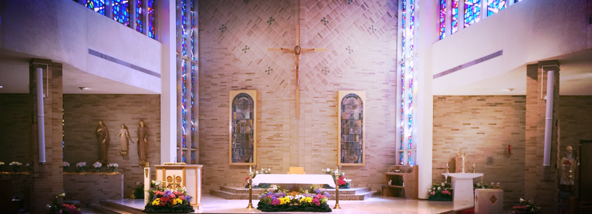 A church with a cross on the altar and stained glass windows.