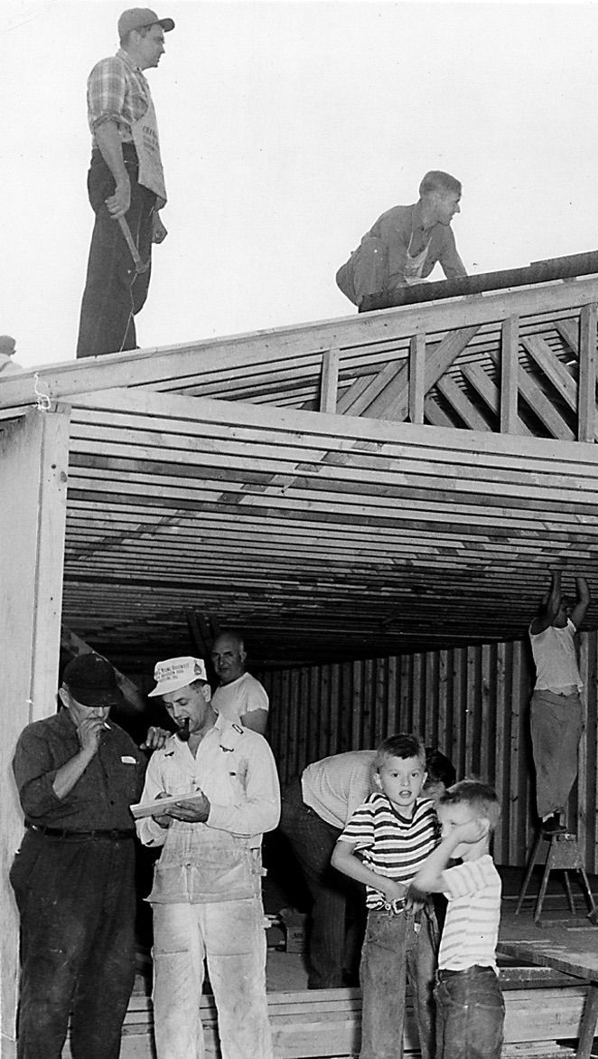 A black and white photo of a group of people working on the church building.