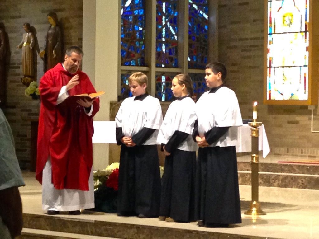 the priest in a red robe is preaching to altar attendants