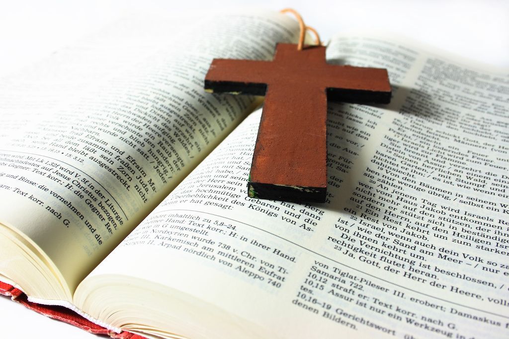 A wooden cross is sitting on top of an open bible