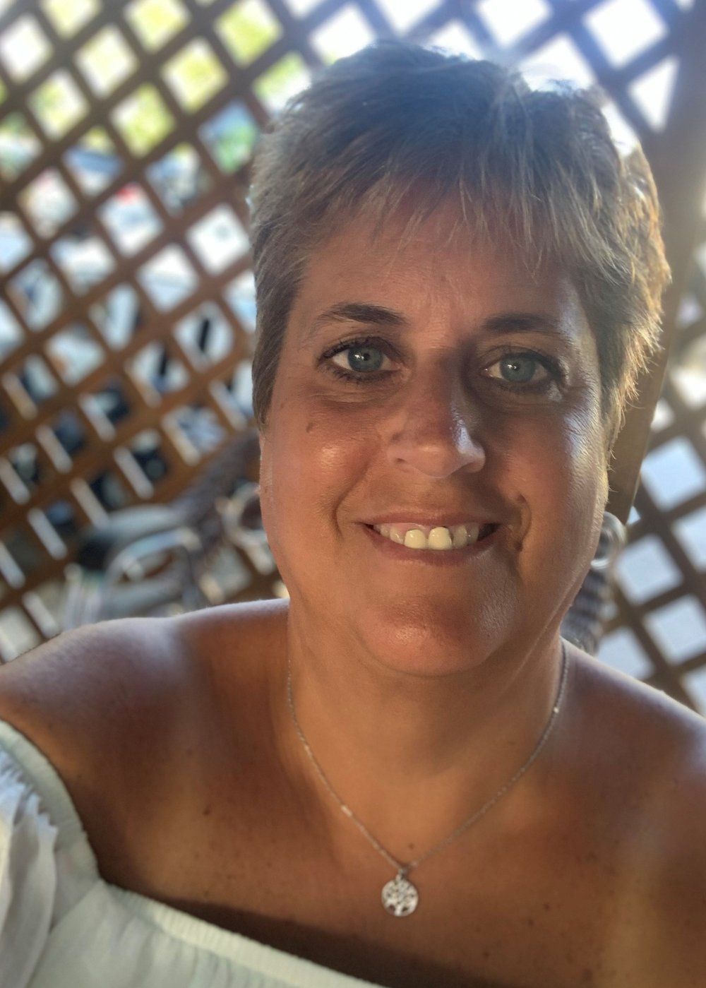 A woman wearing a necklace and earrings is smiling for the camera.