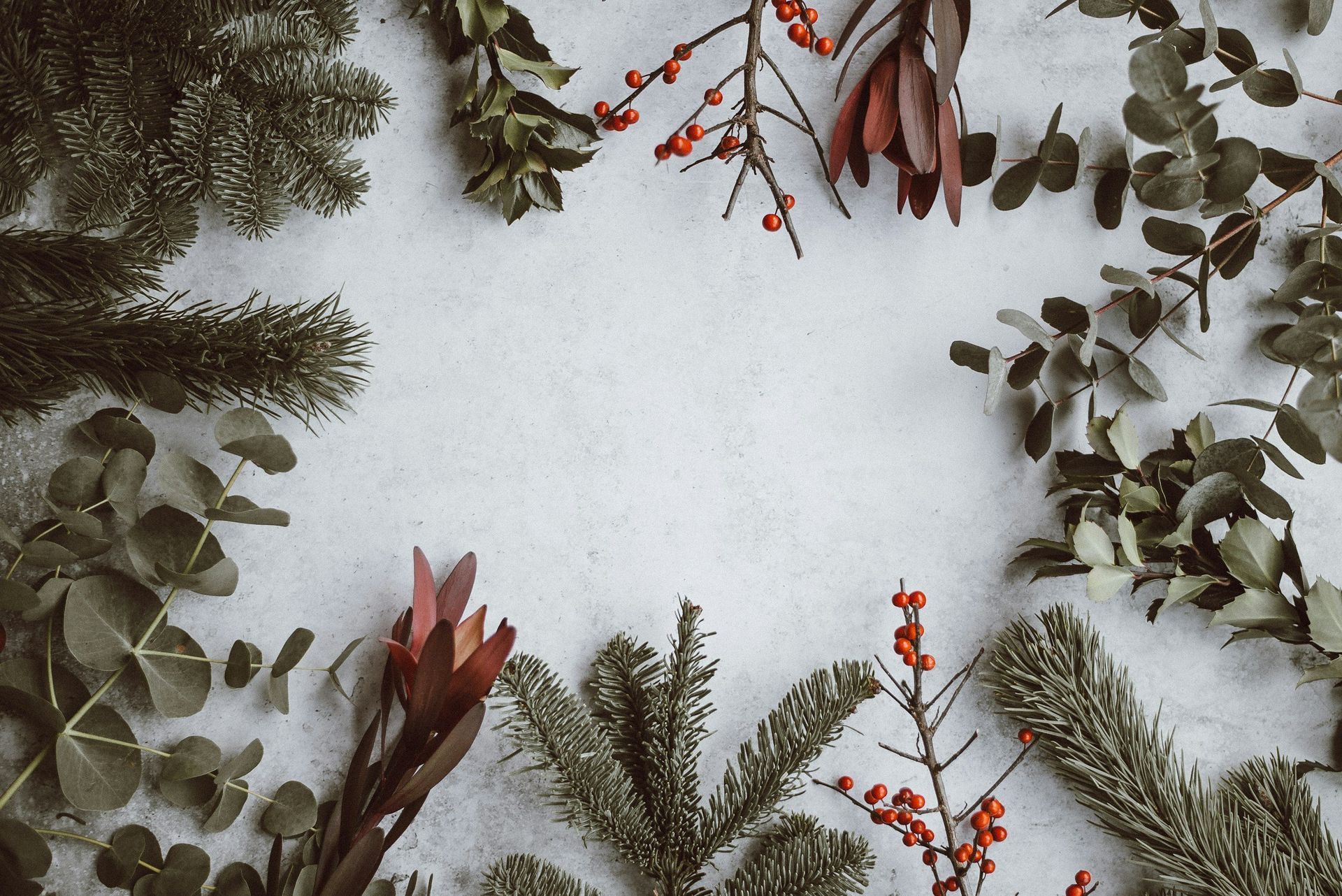 A christmas wreath made of branches and leaves on a white surface.