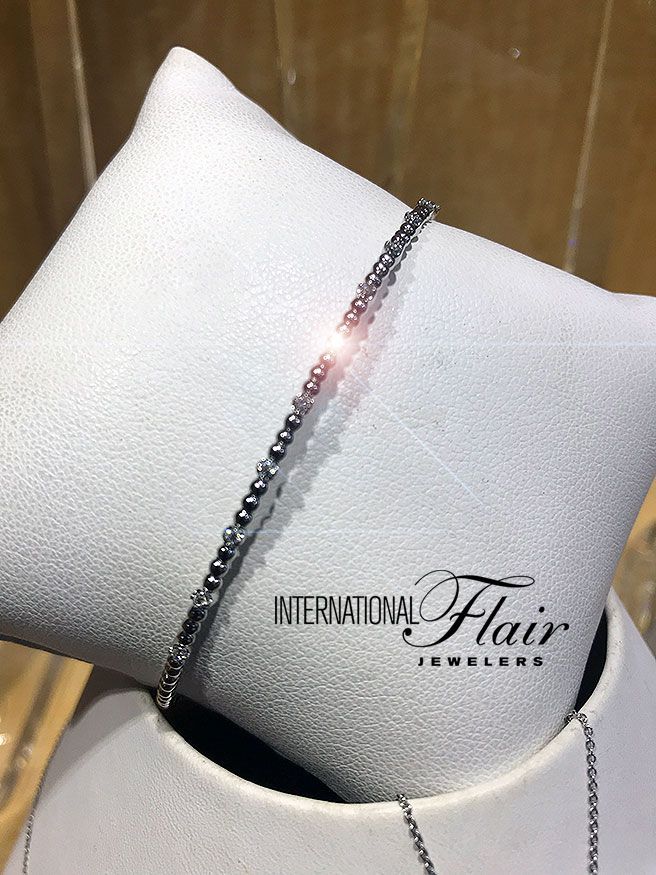 A bracelet is on a white pillow that says international flair