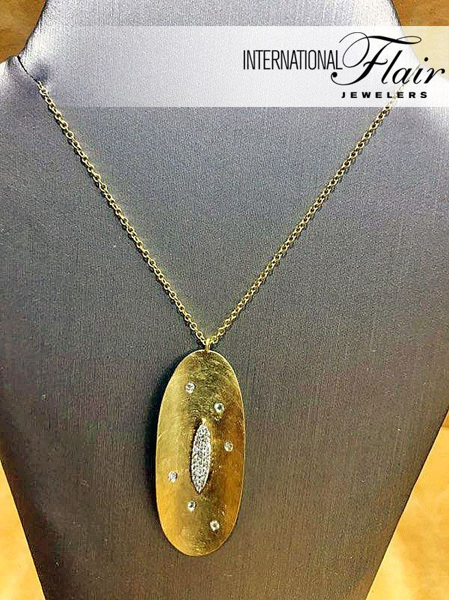 A gold necklace with a diamond pendant is on a mannequin.