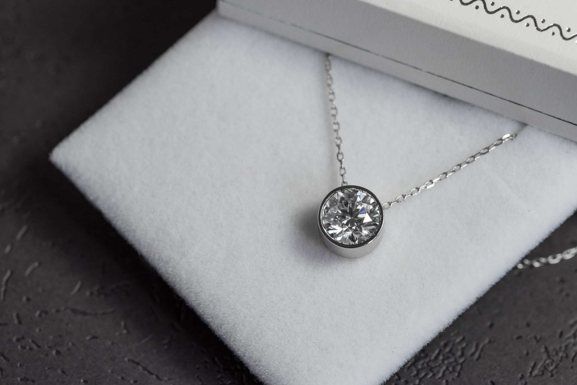 A diamond necklace is sitting on top of a white cloth in a box.