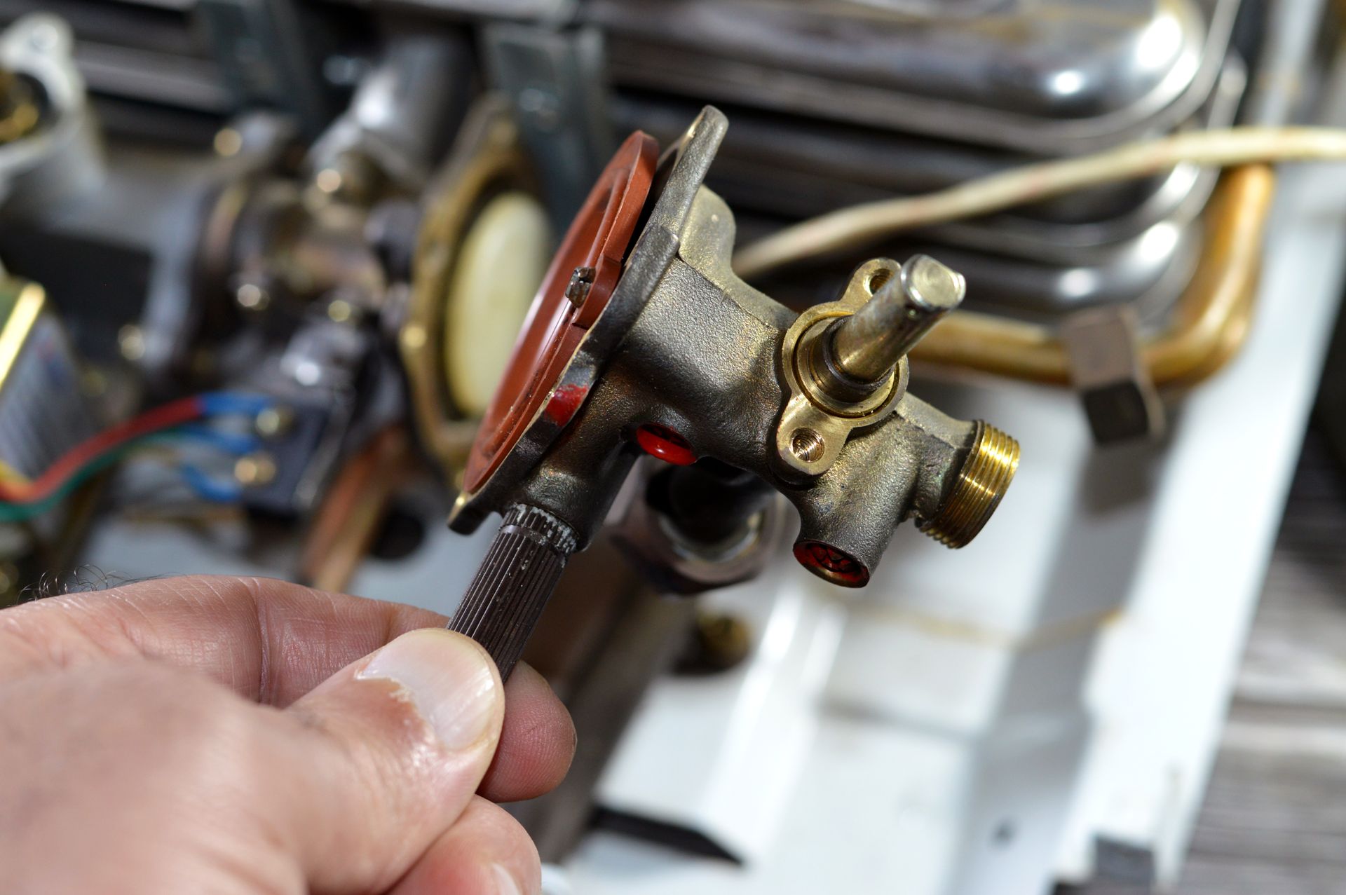 A person is holding a valve in their hand in front of a stove.