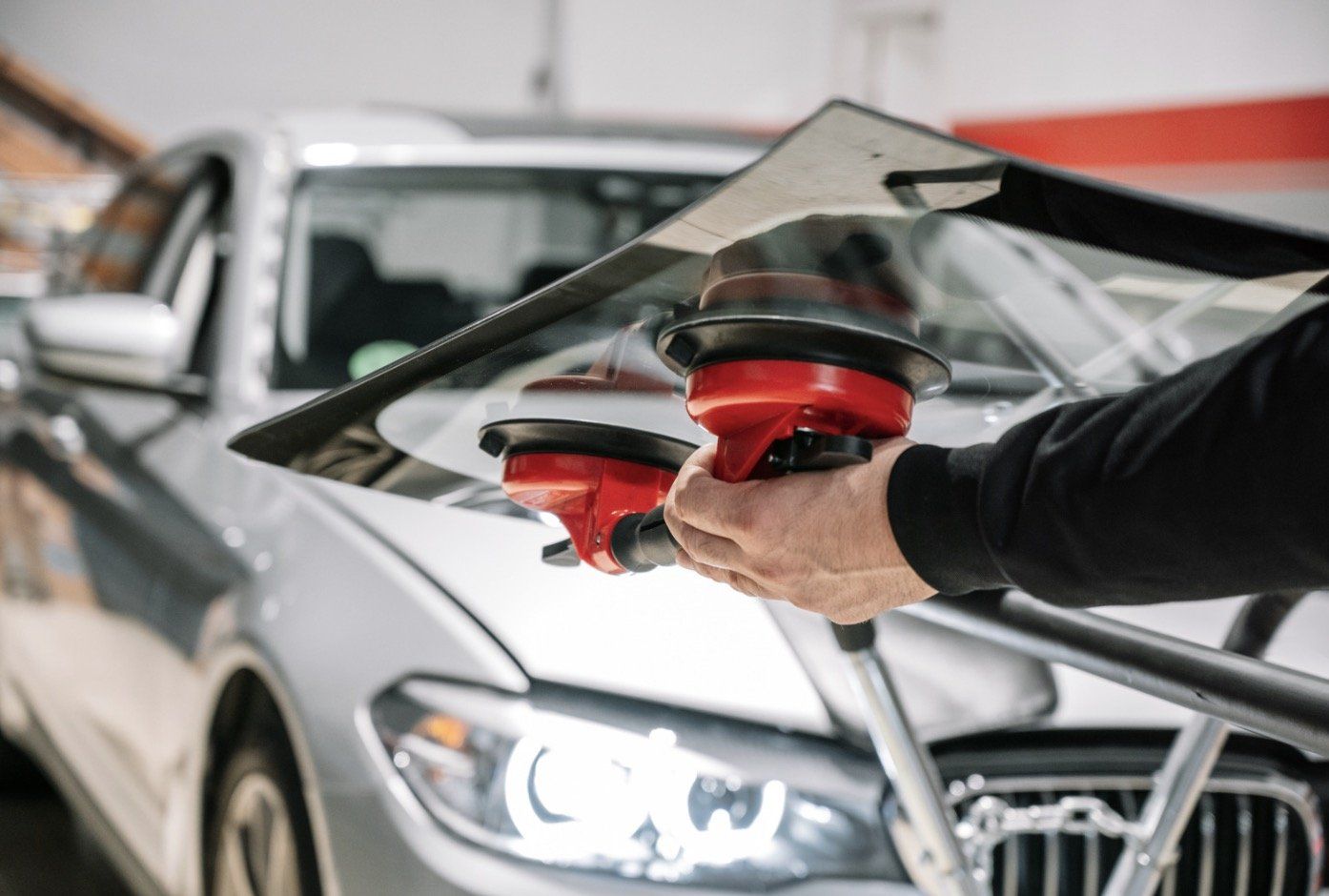 A person using suction cups to install a car windshield.