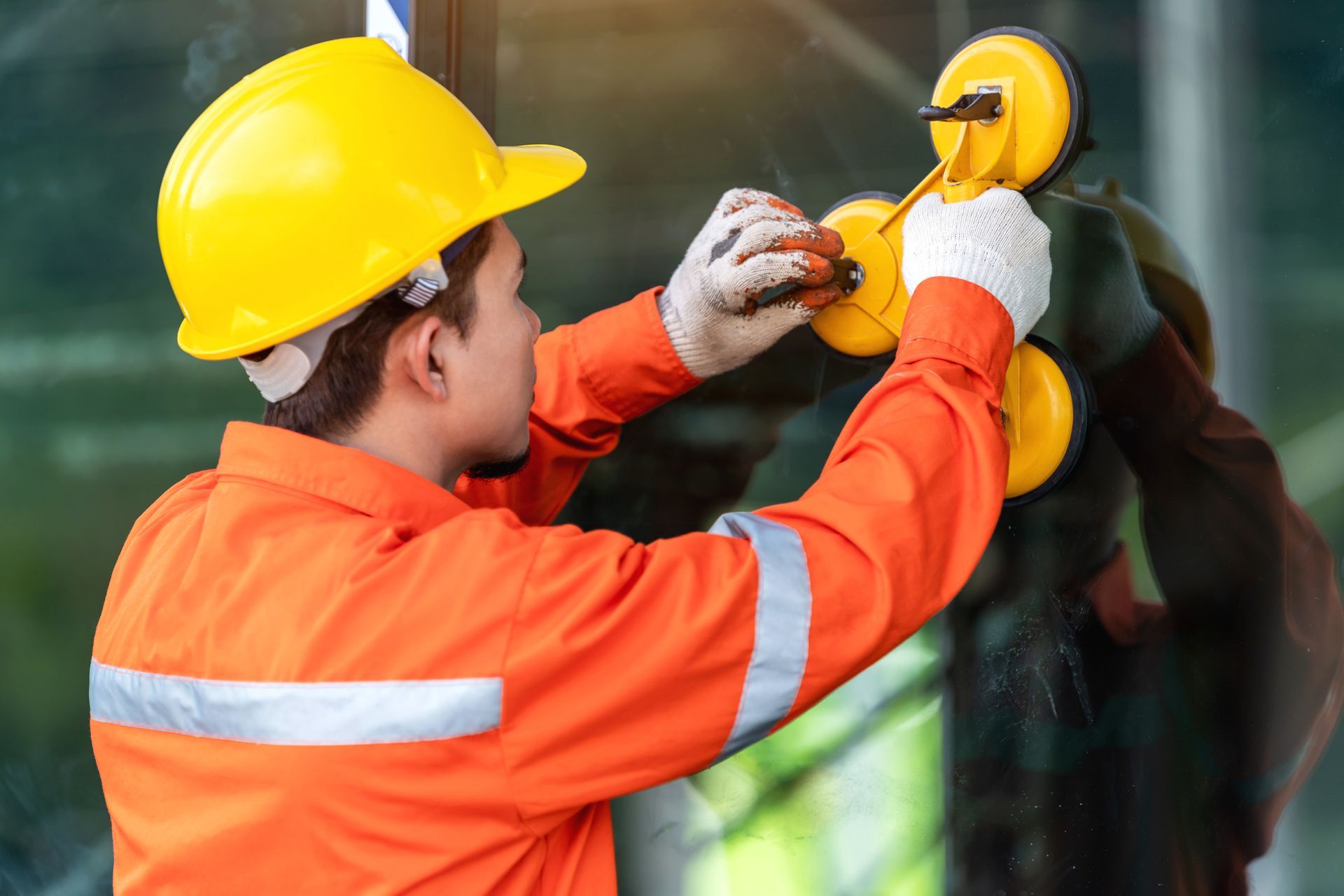 A man wearing a hard hat is working on a window.