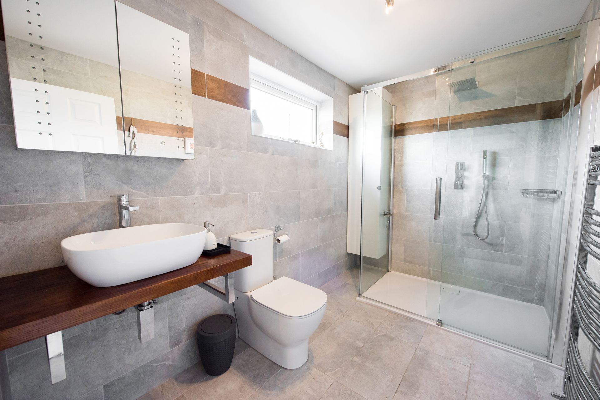 Modern bathroom with white basin, toilet, and frameless shower doors installed.