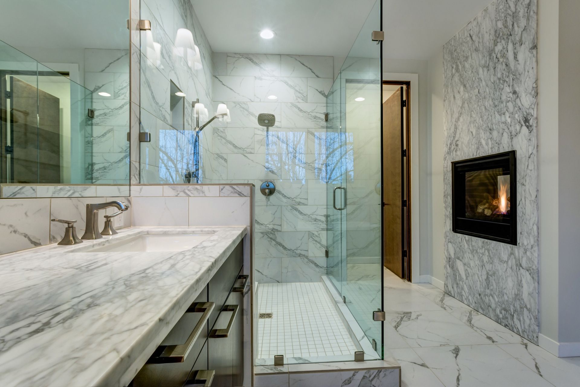 Luxurious marble bathroom with fireplace and elegant frameless shower doors.