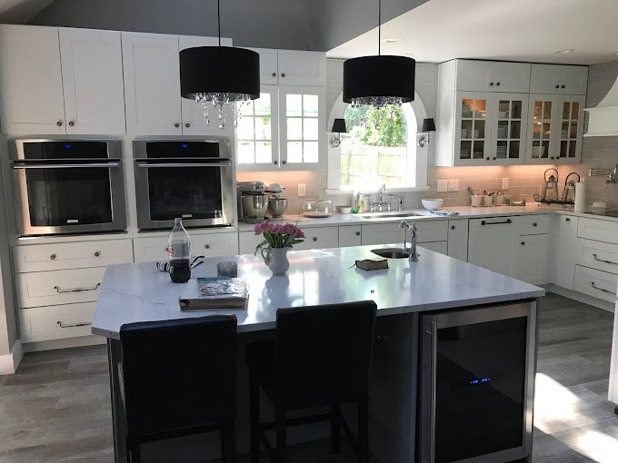 A kitchen with white cabinets, stainless steel appliances and a large island.