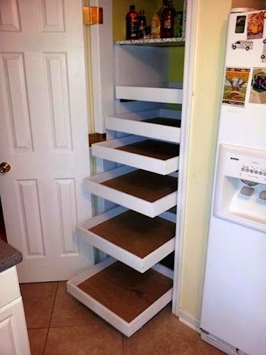 A kitchen with a refrigerator and a pantry with pull out shelves.