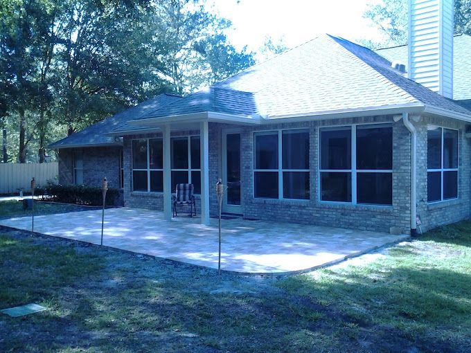 A brick house with a screened in porch and patio.