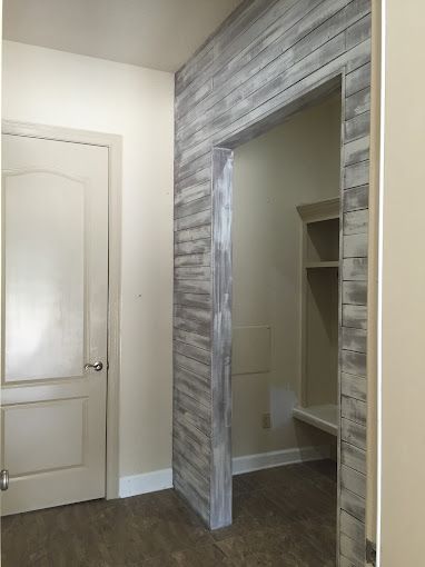 A hallway with a door and a wooden wall.
