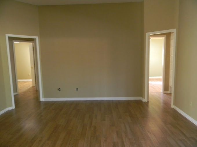 An empty room with hardwood floors and tan walls.