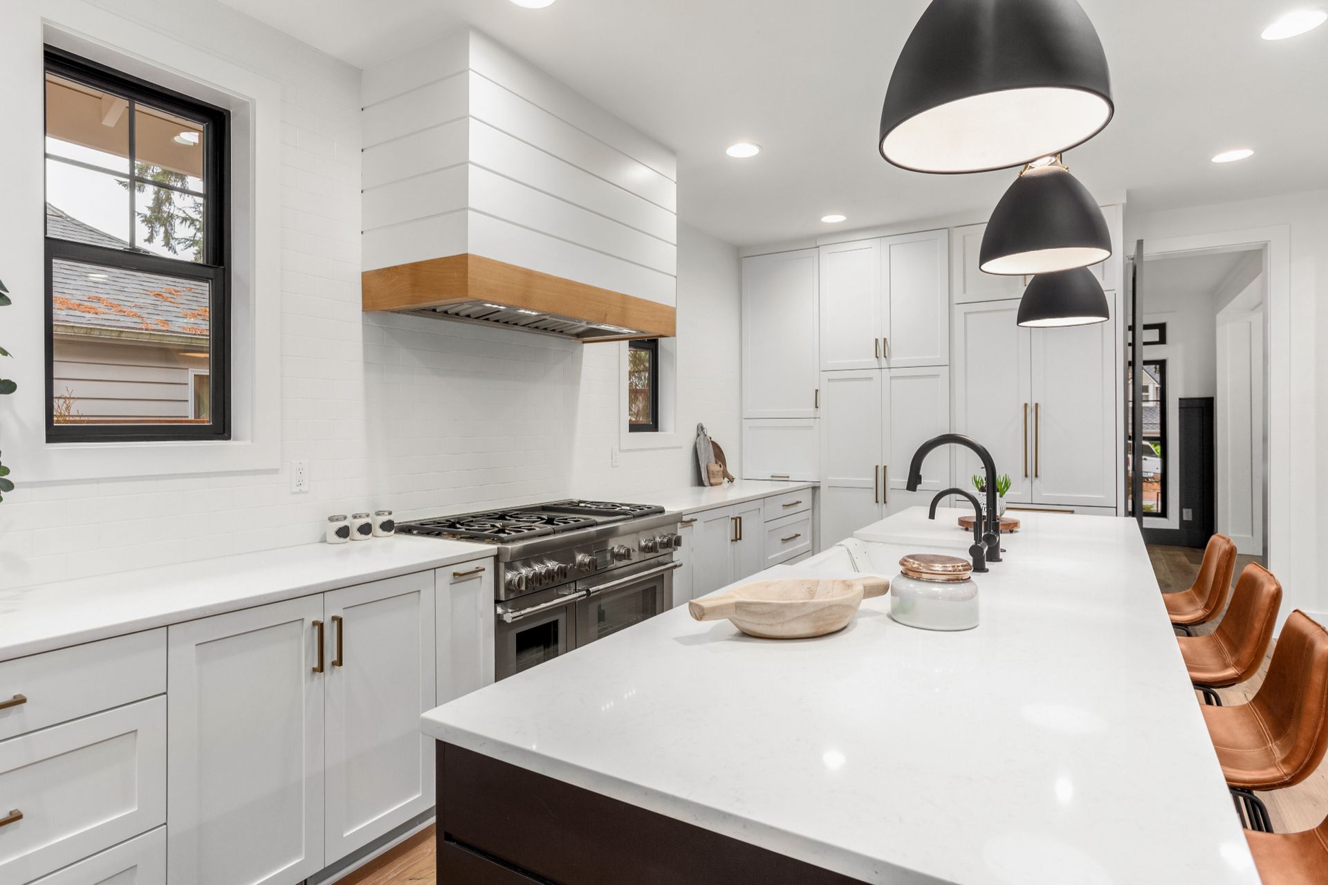 A kitchen with white cabinets, black appliances, and a large island.
