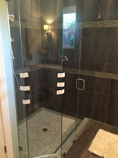 A bathroom with a walk in shower with a glass door.