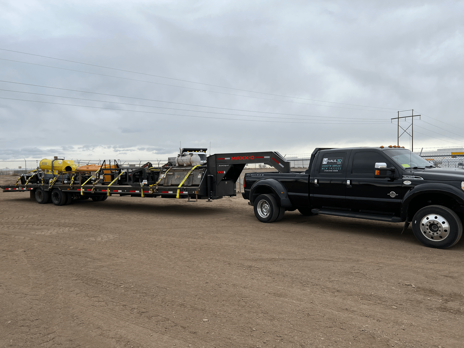 water tanks and other construction equipment safely strapped on to flatbed gooseneck trailer ready to be transported with speed and safety