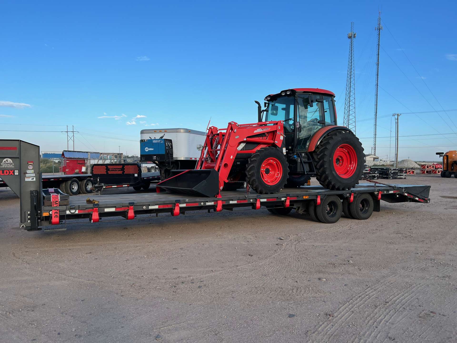 red tractor on flatbed trailer strapped and ready to be transported