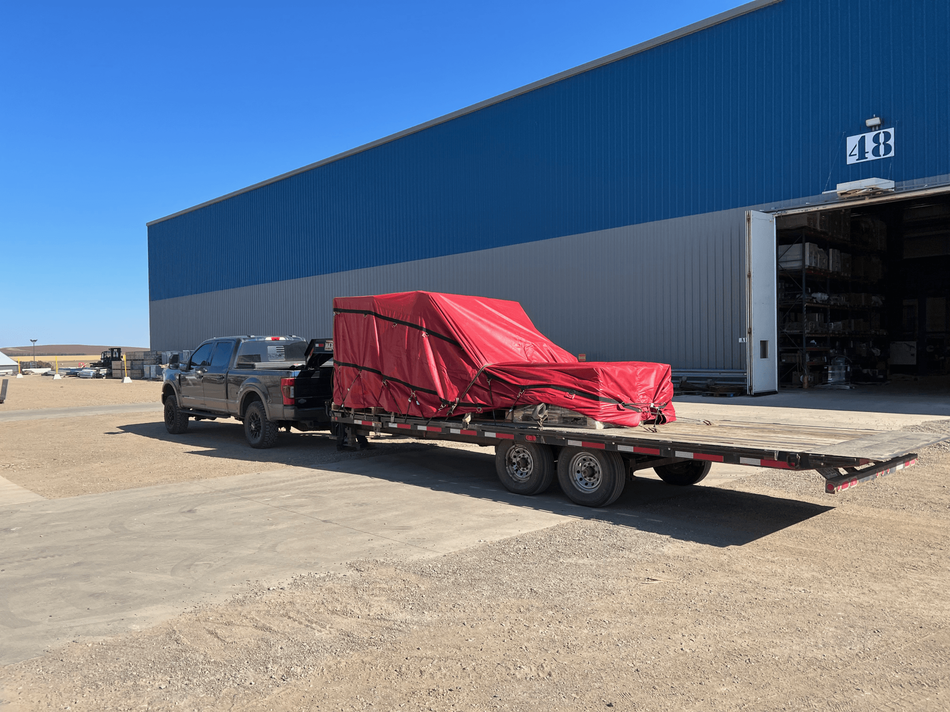 tarped equipment transported on flatbed trailer