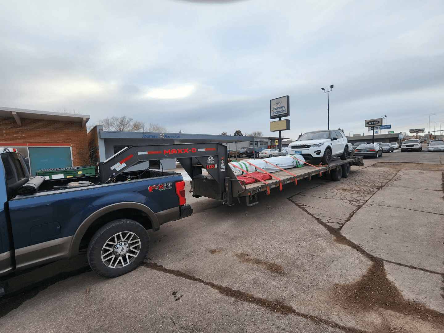 vehicle and construction equipment hauled through denver on flatbed trailer
