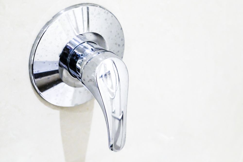 A Close Up Of A Chrome Shower Faucet On A White Wall — DMK Plumbing in Port Macquarie, NSW