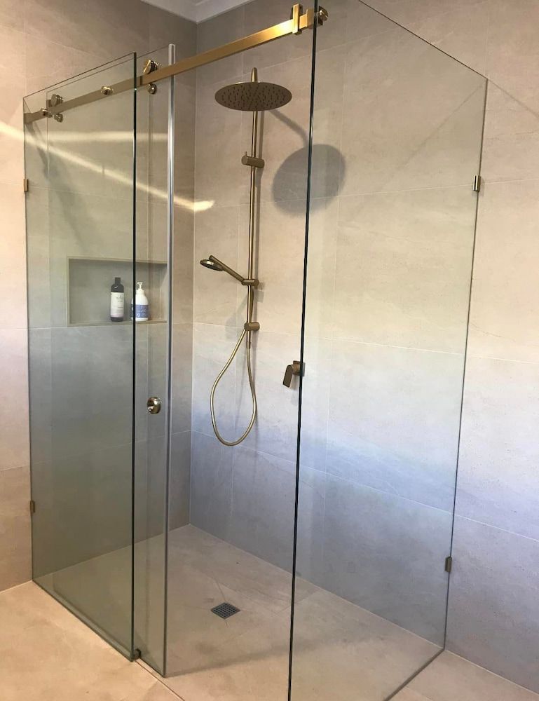 A Bathroom With A Sliding Glass Shower Door And A Shower Head — DMK Plumbing in Crescent Head, NSW