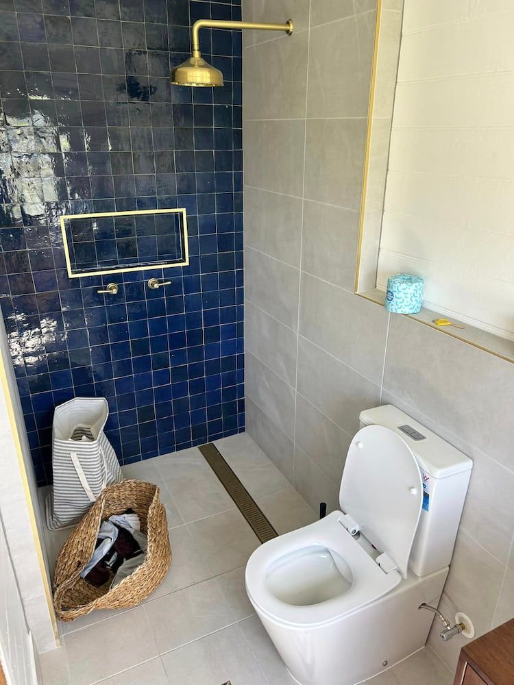 A Bathroom With A Toilet, Shower And Blue Tiles — DMK Plumbing in Crescent Head, NSW