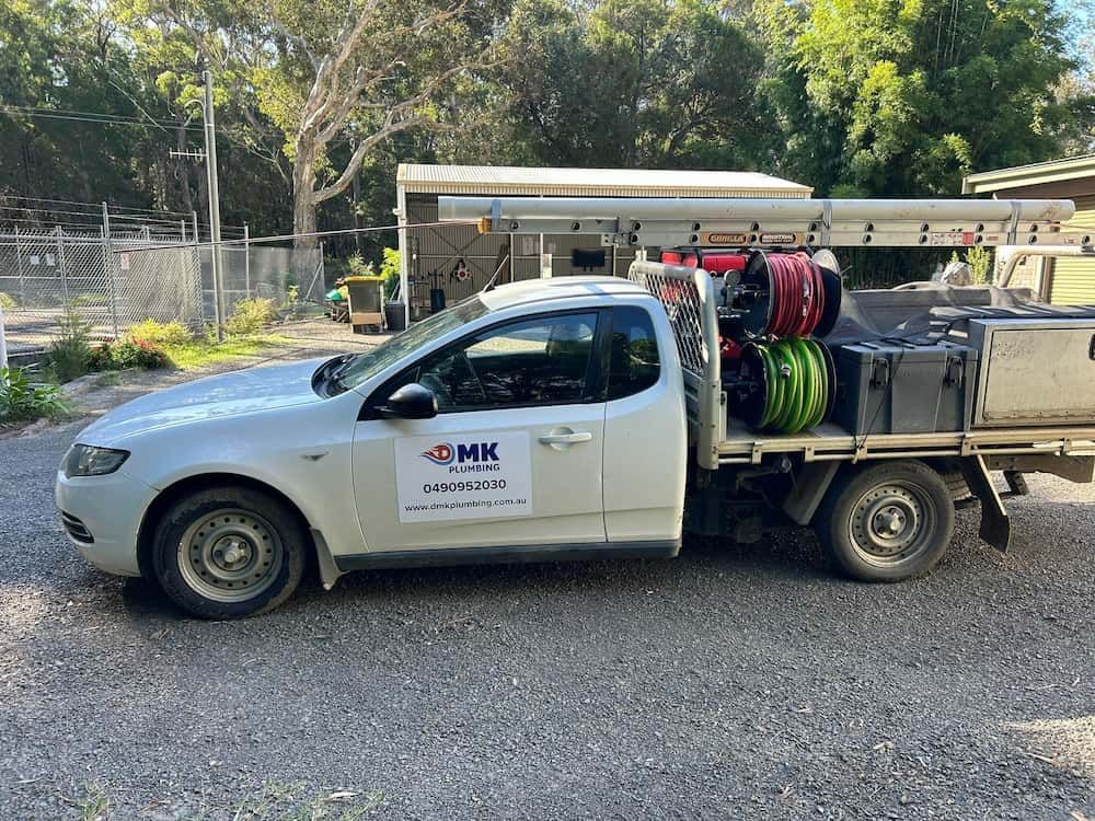A White Truck Is Parked In A Gravel Lot — DMK Plumbing in Crescent Head, NSW