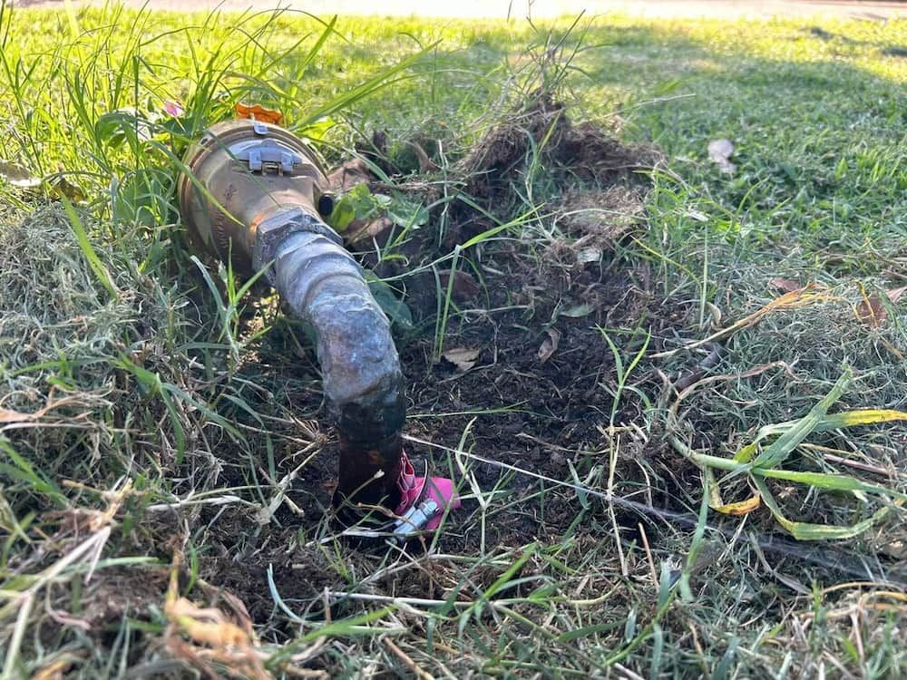 A Hose Is Sticking Out Of The Ground In The Grass — DMK Plumbing in Crescent Head, NSW