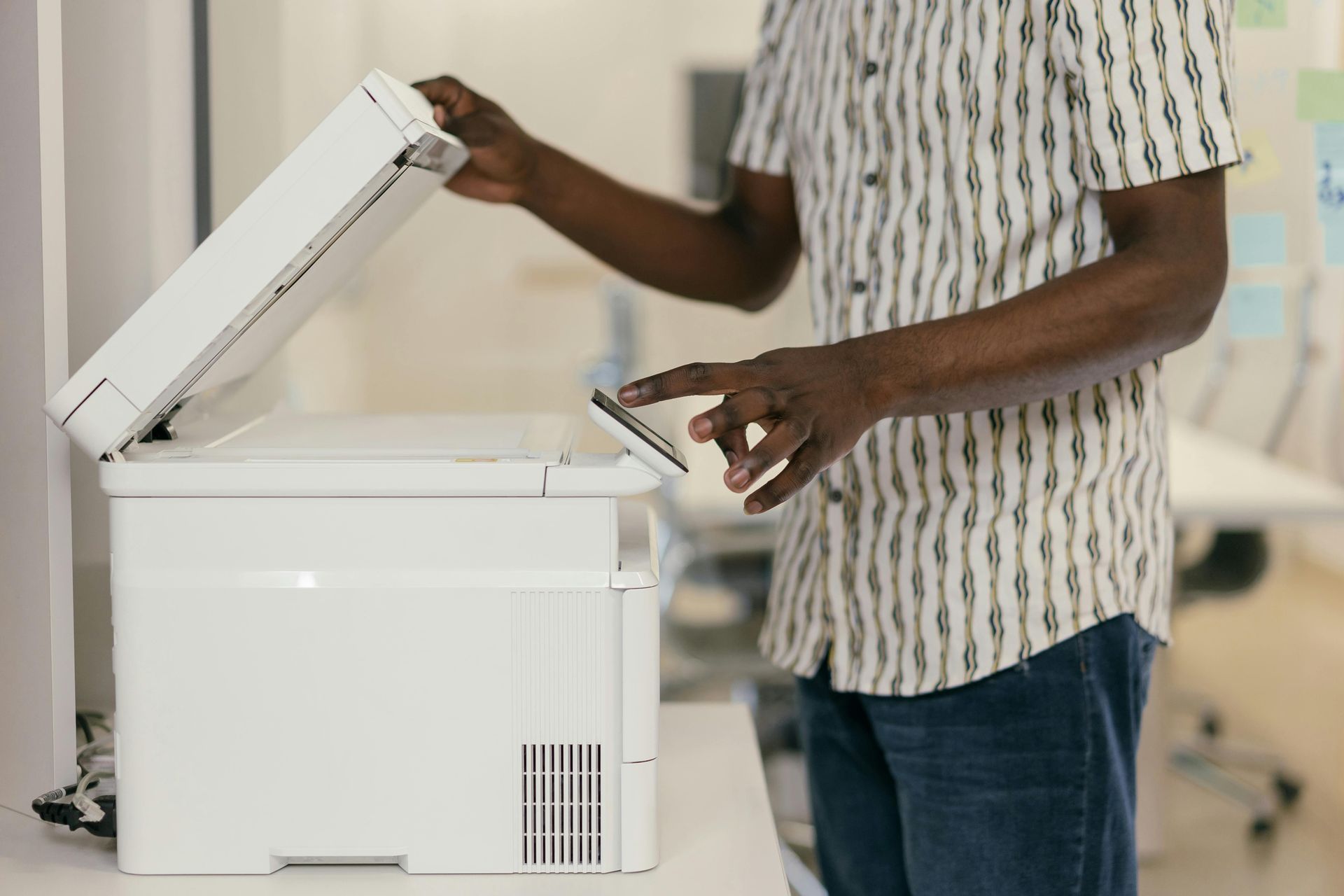 A man is using a printer to scan a piece of paper.