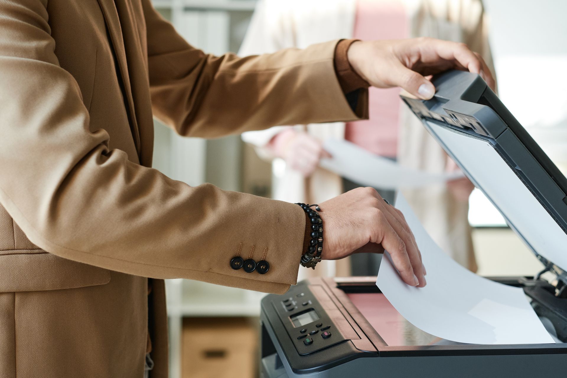 A man is using a printer to scan a piece of paper.