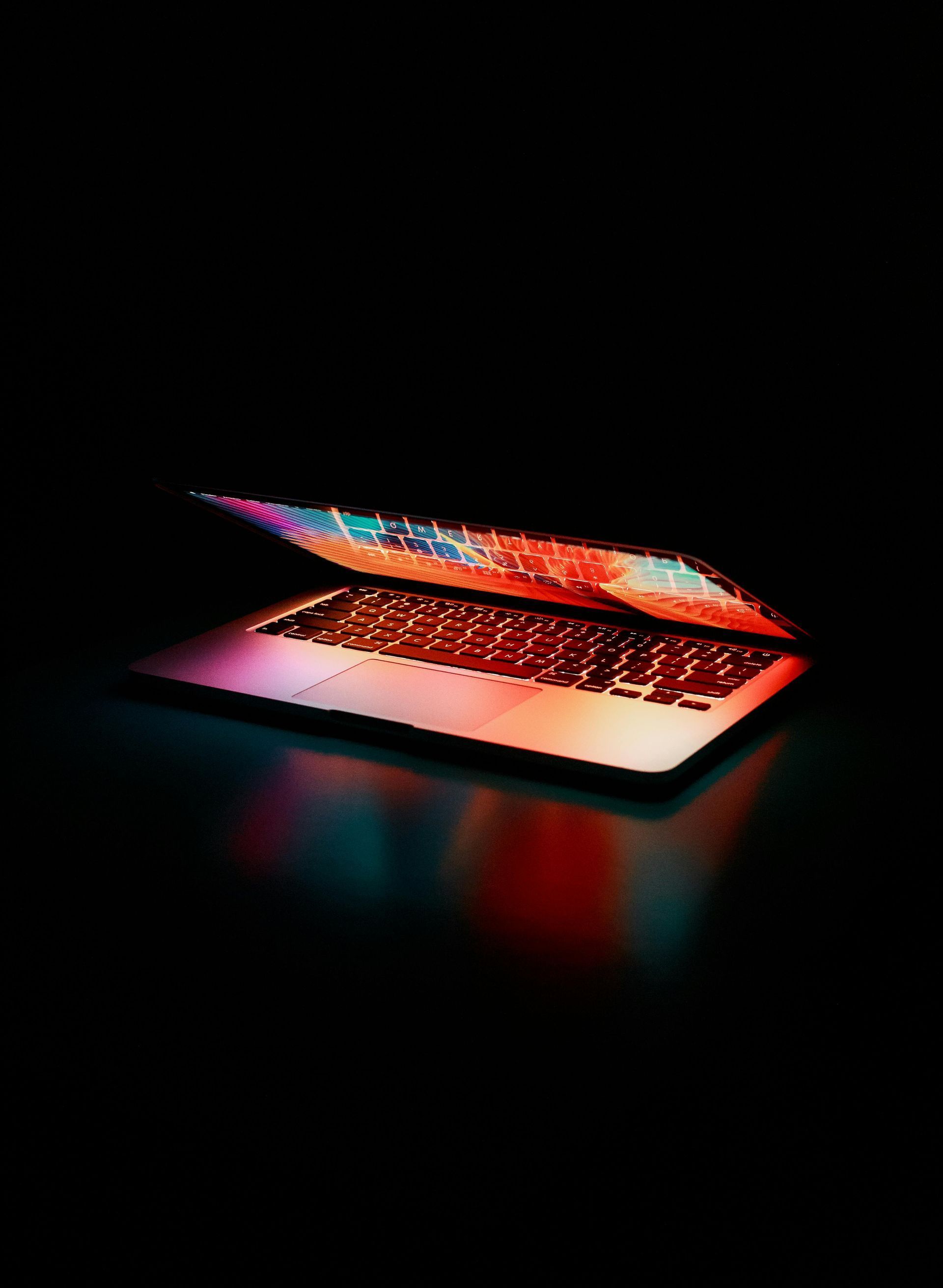 A laptop computer is open and sitting on a table in the dark which represents our copywriting service.