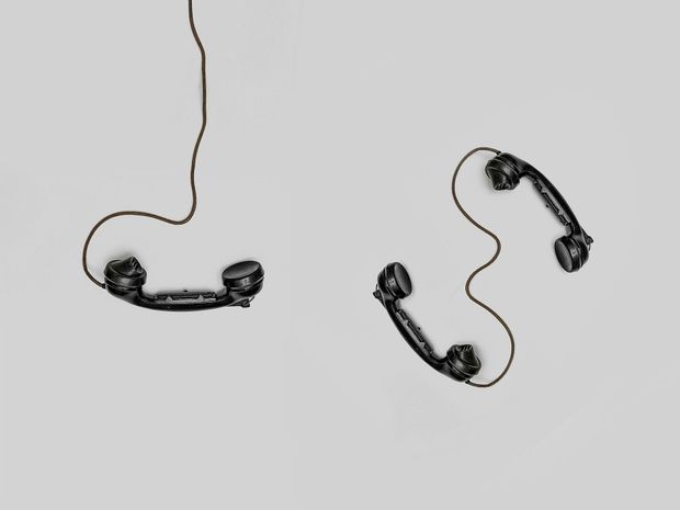 Two old fashioned telephones hanging from a wire on a grey background that aligns with the message to contact us.