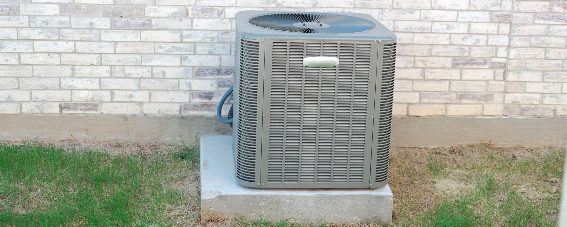 Two technicians in hard hats repairing an air conditioning unit on a rooftop.