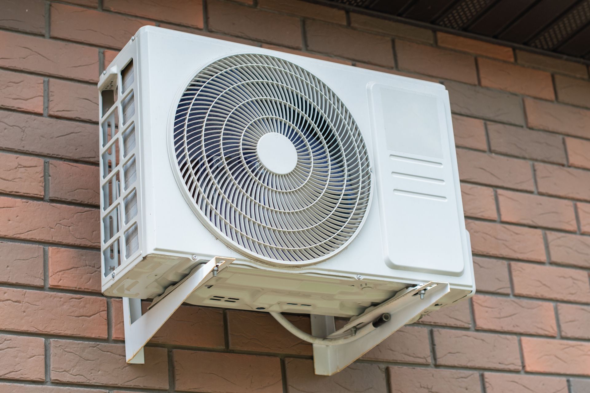 White air conditioning unit mounted on a brick wall.