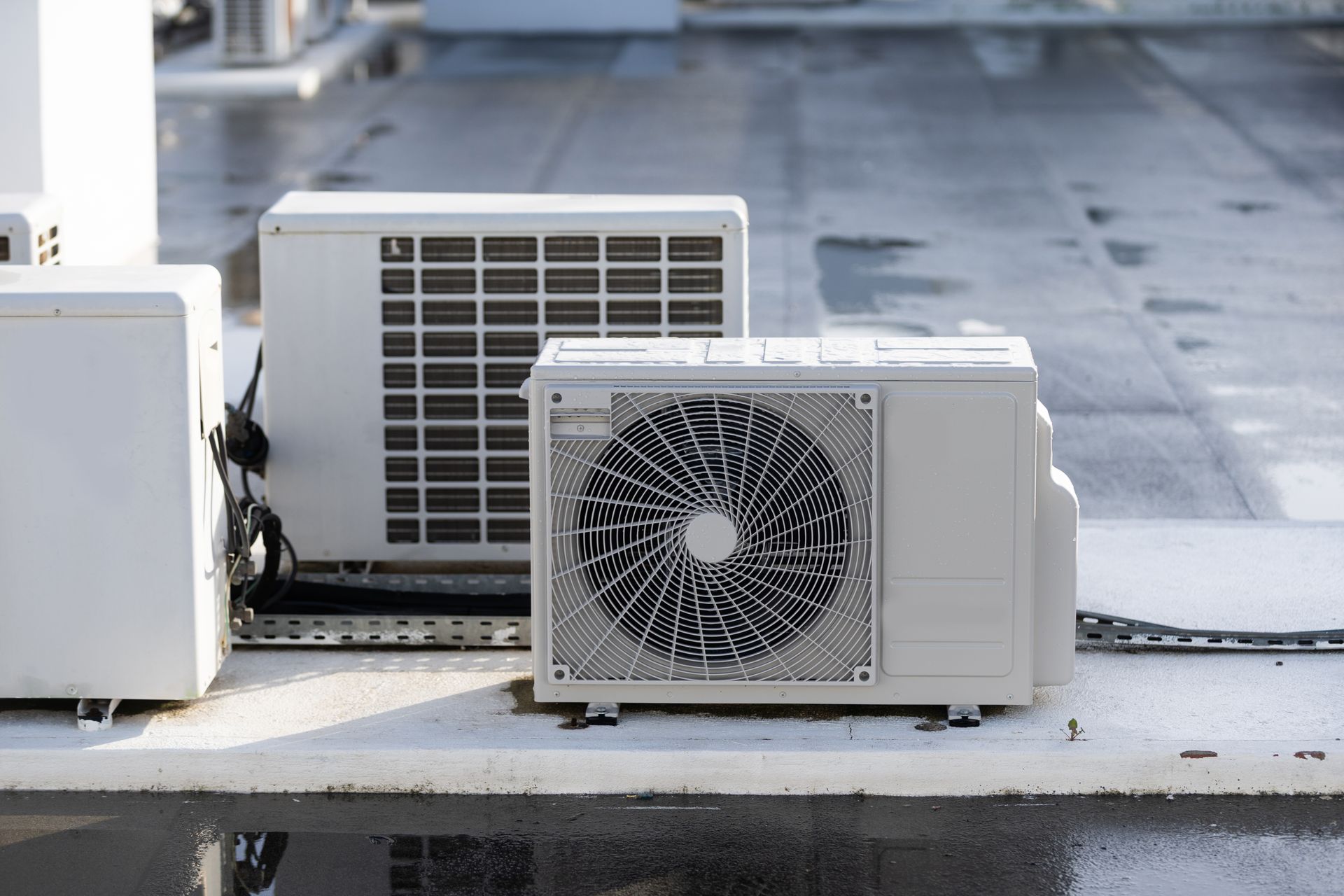 White air conditioning units on a wet rooftop.