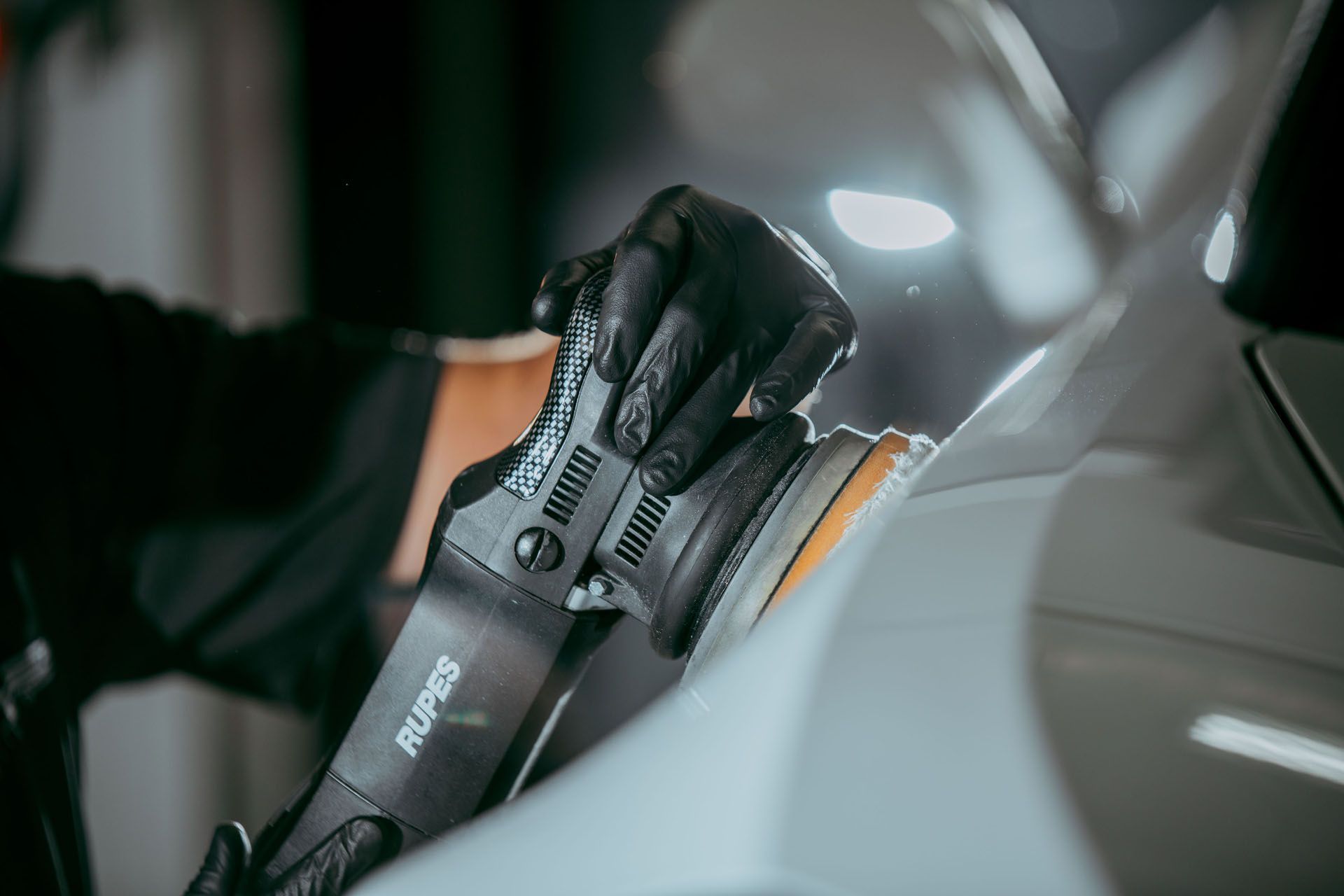 A person is polishing a car with a machine.