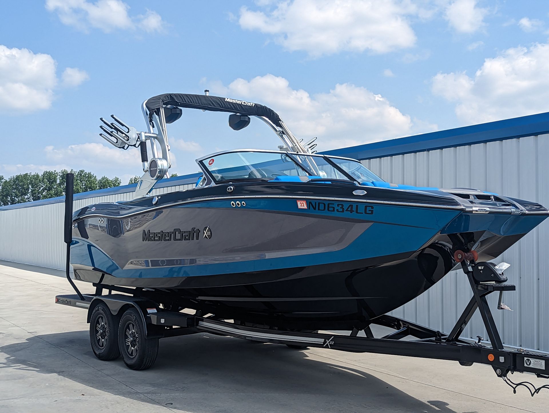 A blue and gray boat is parked on a trailer in front of a building.