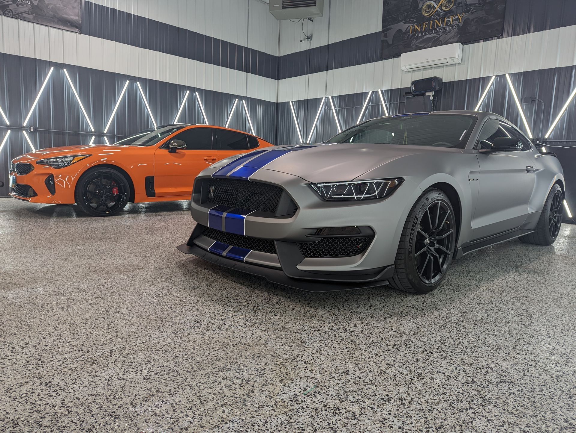 Two ford mustangs are parked next to each other in a garage.
