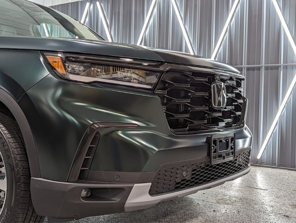 A black honda ridgeline is parked in a showroom.