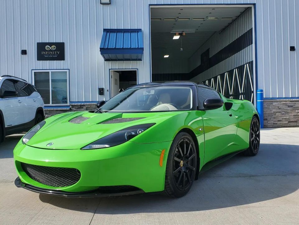 A green sports car is parked in front of a building.
